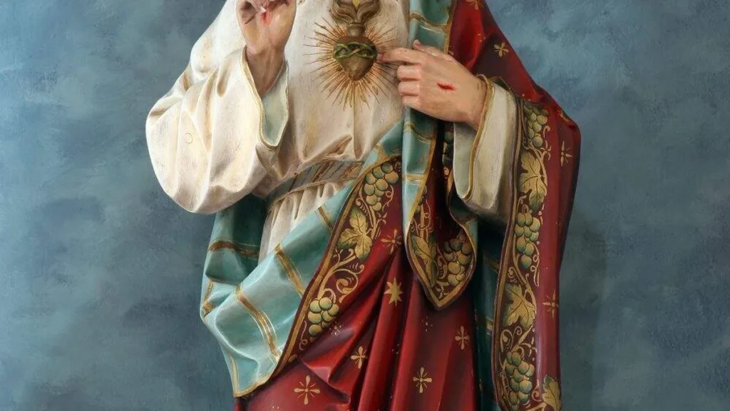 Imagem Imagem do Sagrado Coracao de Jesus sobre fundo azul e flores brancas ao lado do artigo Jesus com o coração para fora