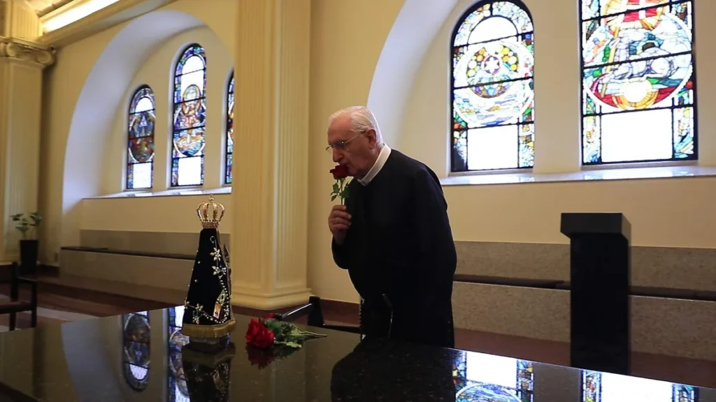Padre Pasquoto dando uma flor para Nossa Senhora Aparecida na Capela dos Apóstolos