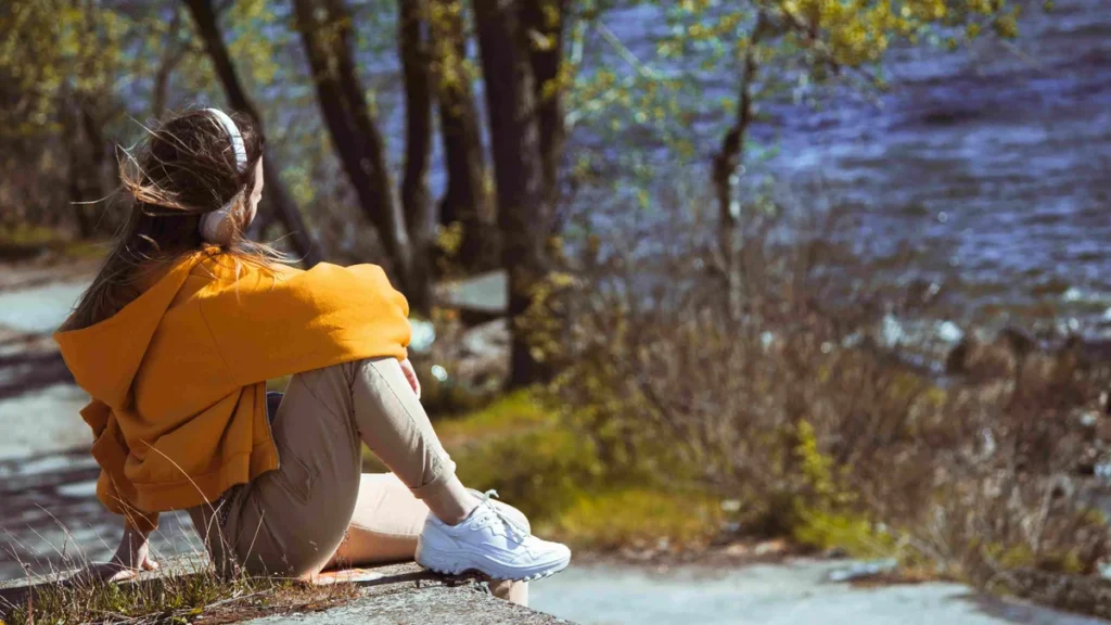 Imagem moca ouvindo musica olhando para a natureza do artigo 9 músicas para quando nos faltar a coragem