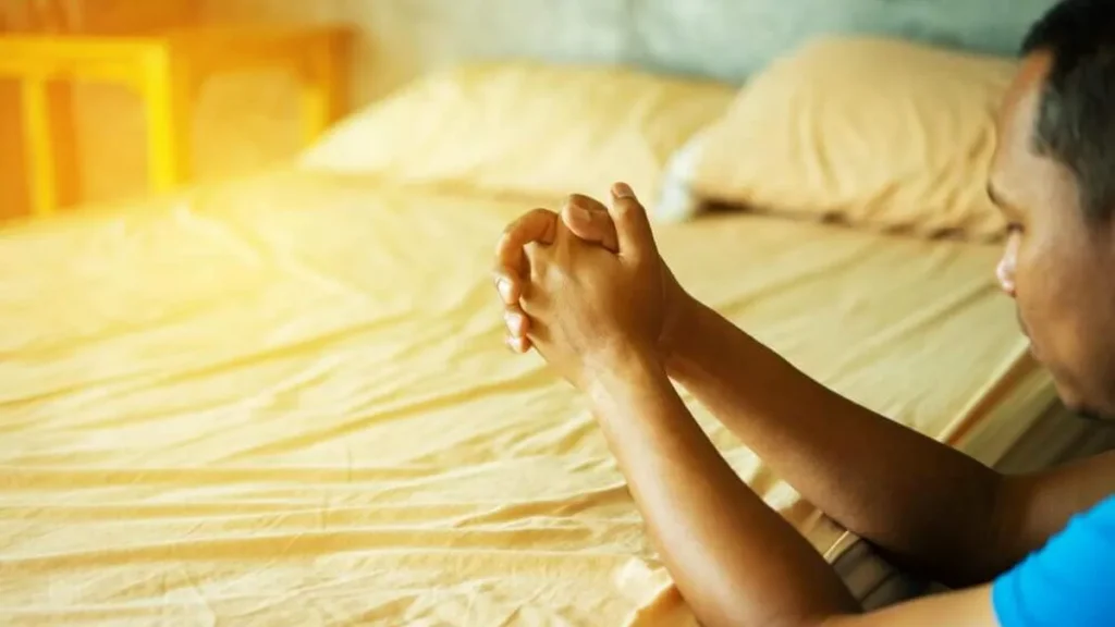 Imagem homem rezando sentado cama do artigo Por que o meu pedido 'nunca' é atendido por Deus?