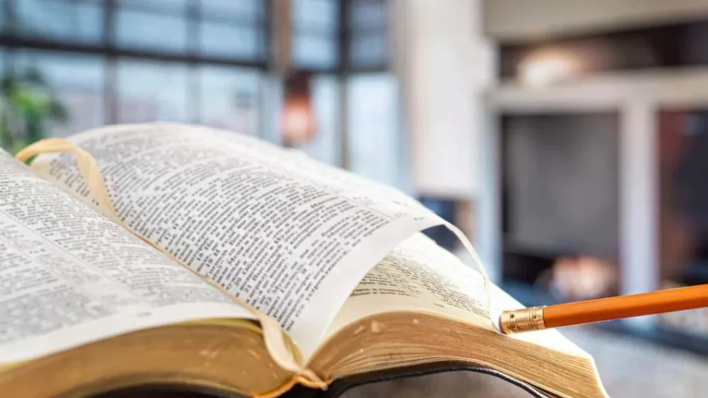 Imagem Um homem segura uma biblia com um lapis no contexto da sala de estar. do artigo Vaticano divulga curso on-line gratuito sobre teologia e prática da Sinodalidade