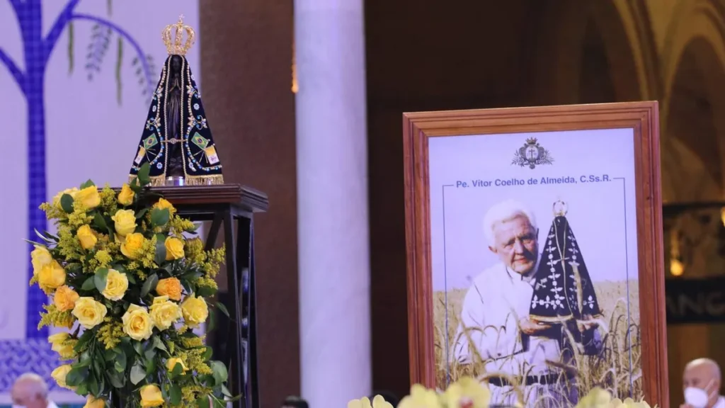 Imagem Imagem de Nossa Senhora Aparecida ao lado de um quadro do Padre Vitor do artigo Tríduo: Santuário Nacional celebra 35 anos da Páscoa de Pe. Vitor