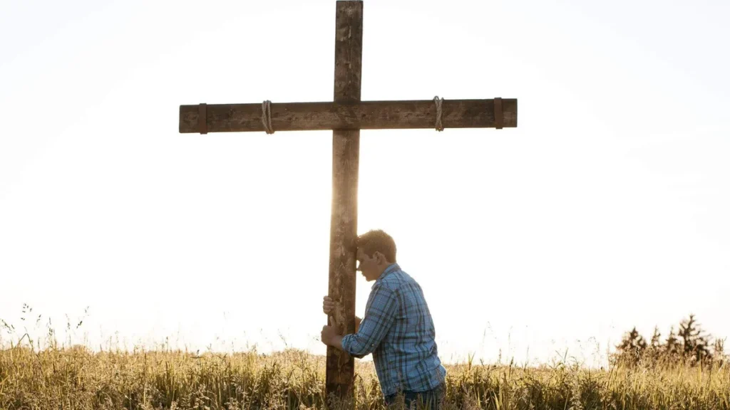 Imagem pessoa segurando cruz no campo do artigo O brilho da Juventude que tem Deus como o sentido da vida