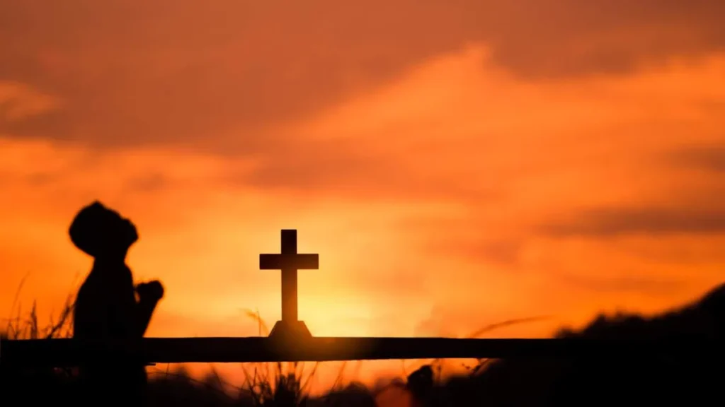 Imagem pessoa orando no por do sol com cruz de fundo do artigo Você sabe o que significa “Kyrie Eleison”?
