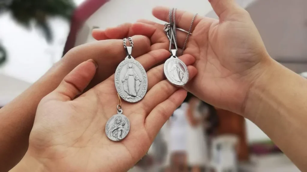 Imagem maos segurando a medalha de nossa senhora do artigo Quais as diferenças entre sacramento e sacramentais?