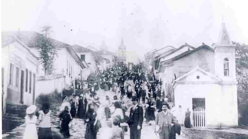 Romeiros na Rua Calçada, atual ladeira Monte Carmelo, em Aparecida. Ao fundo, Basílica Histórica.