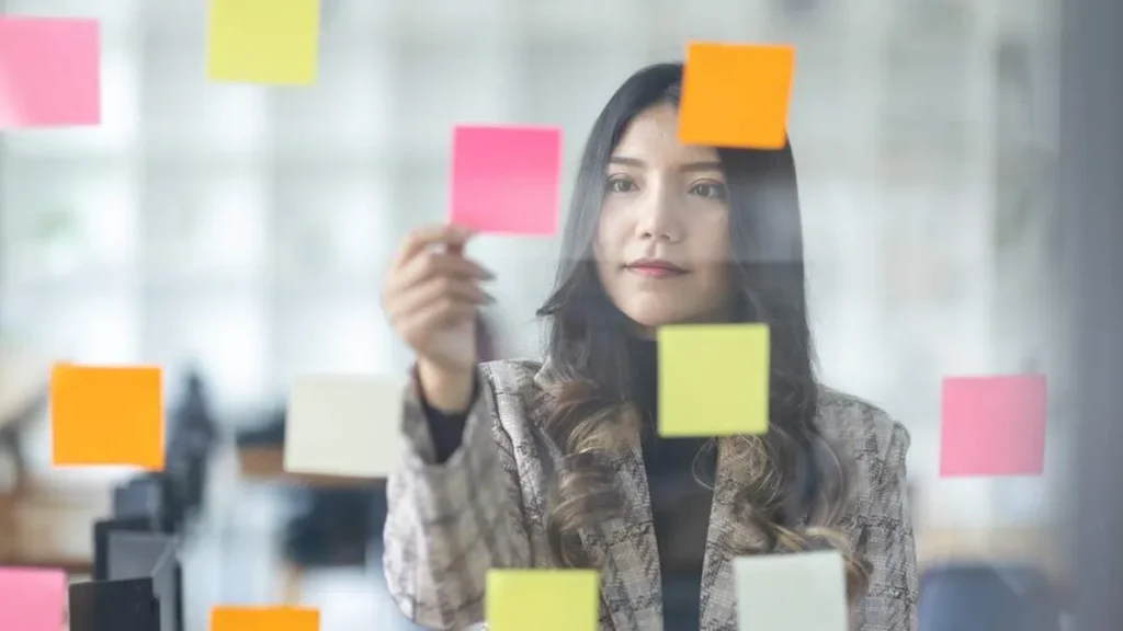 Imagem mulher planejando por meio de post its do artigo 4 movimentos para organizar suas prioridades