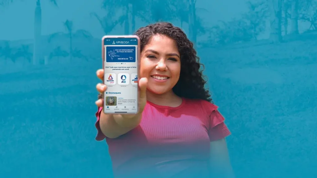 Imagem Lais segurando celular com aplicativo Aparecida na tela do artigo Fé que aproxima: aplicativo Aparecida completa 2 anos