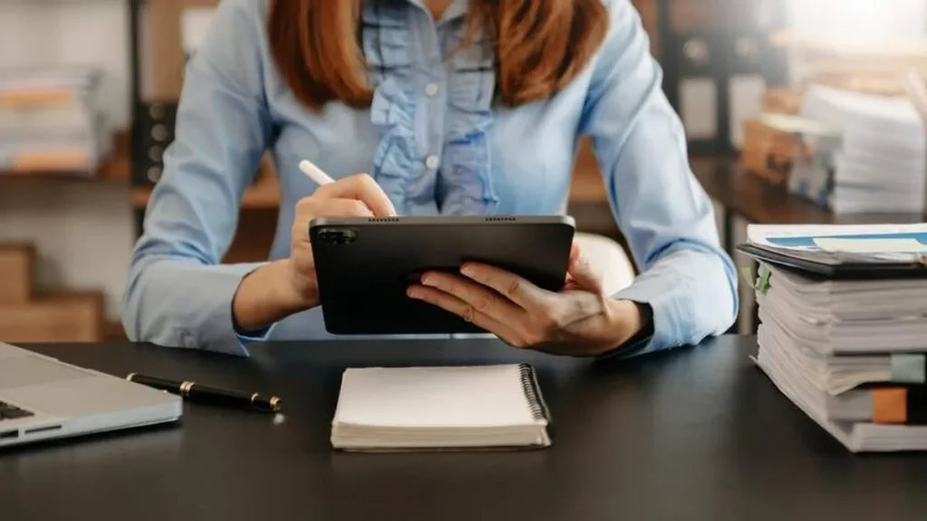Imagem mulher mexendo em tablet no trabalho do artigo 6 tendências no mercado para 2023
