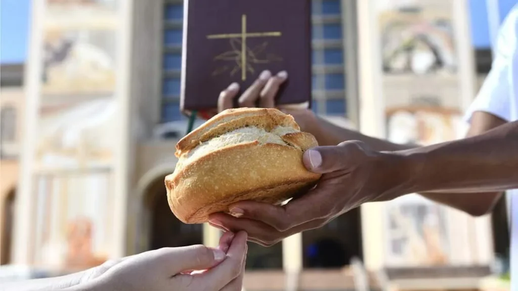 Imagem Mao entrega pao e Biblia do artigo Dai-lhes vós mesmos de comer