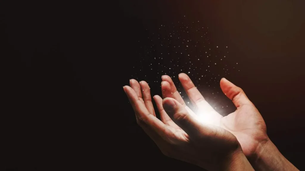 Imagem Maos no escuro com luz saindo delas do artigo 3 fatos da Igreja que a ciência não explica