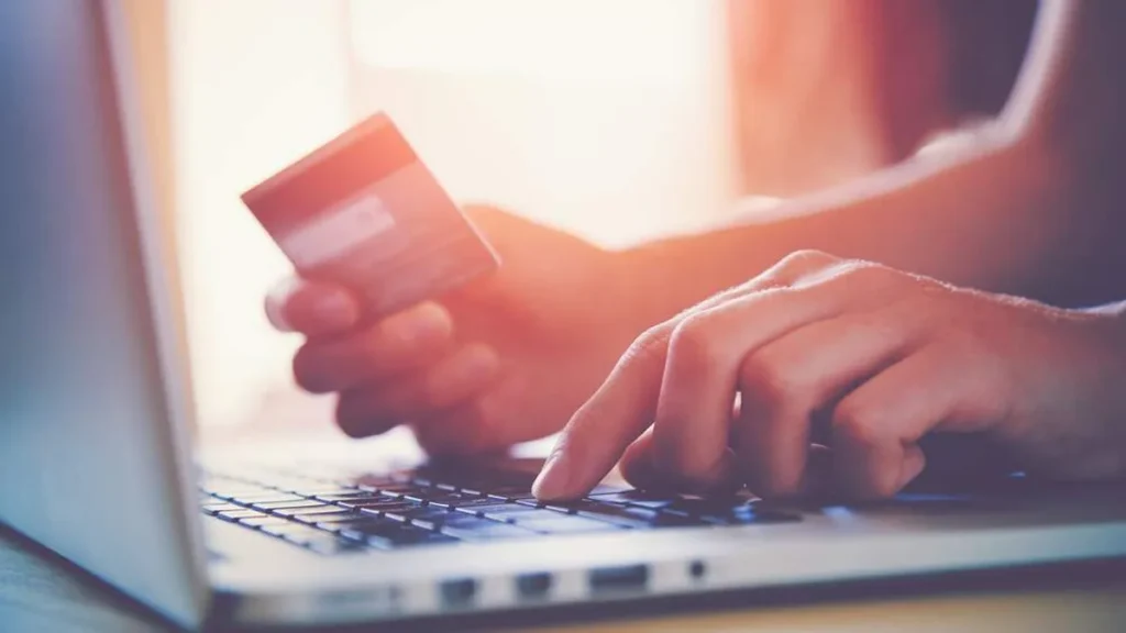 Imagem maos segurando cartao de credito e mexendo no notebook do artigo 5 afirmações do Papa Francisco sobre o consumismo