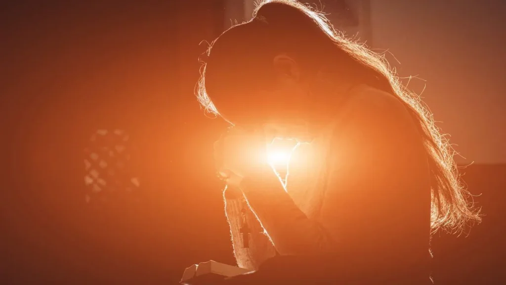 Imagem Mulher catolica rezando com luz de fundo do artigo Estou vivendo os valores de uma mulher católica?
