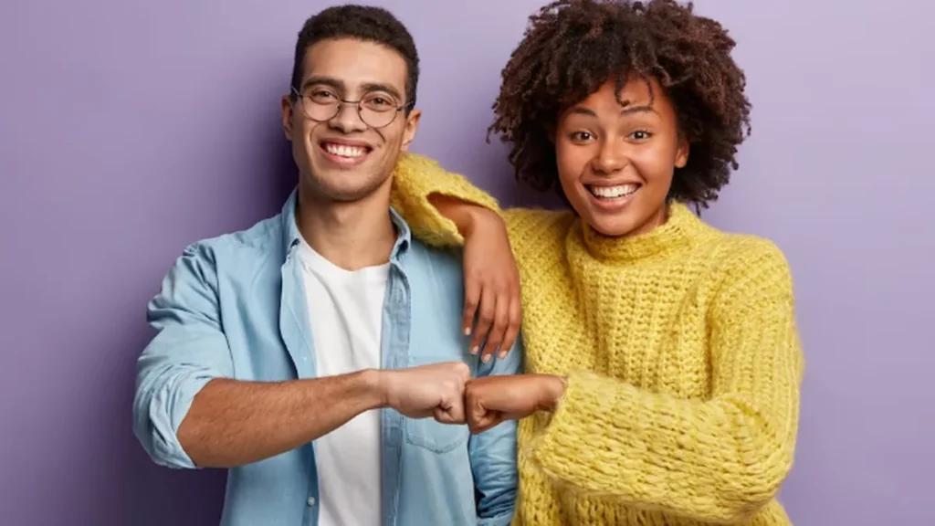 Dois jovens, um homem e uma mulher, sorrindo e olhando para frente