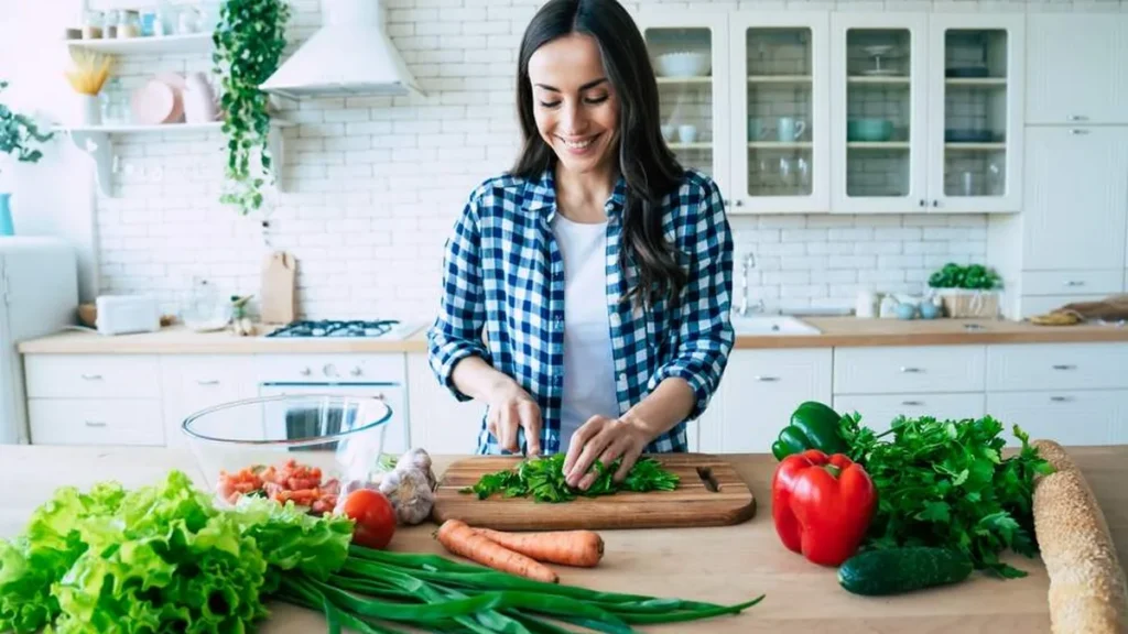 Moça na cozinha cortando vegetais e hortaliças