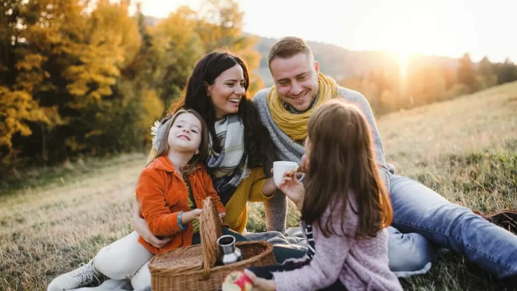 Imagem familia feliz reunida em um piquenique do artigo Receitas de Piquenique: sanduíche de frios e bolo de chocolate