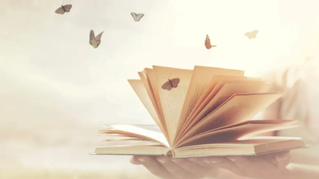 Imagem Livro aberto com folhas voando e borboletas em cima delas do artigo Trocar as armas por livros...
