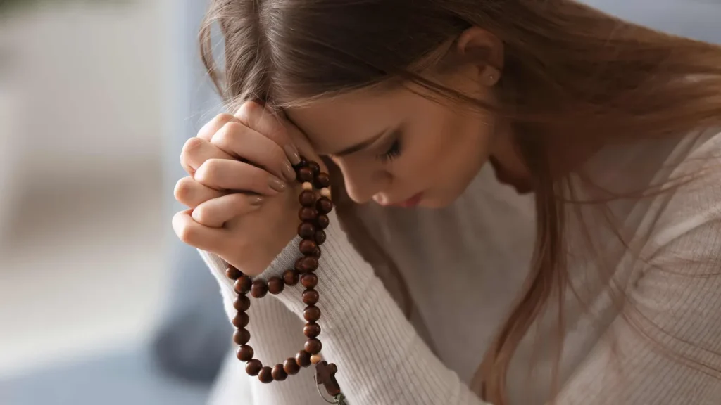 Imagem jovem mulher rezando o terco do artigo Aprenda a rezar o Rosário do Espírito Santo