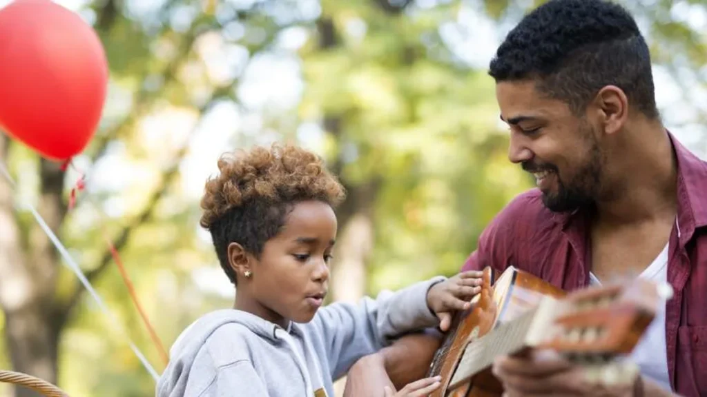 Pai tocando violão e o filho interessado