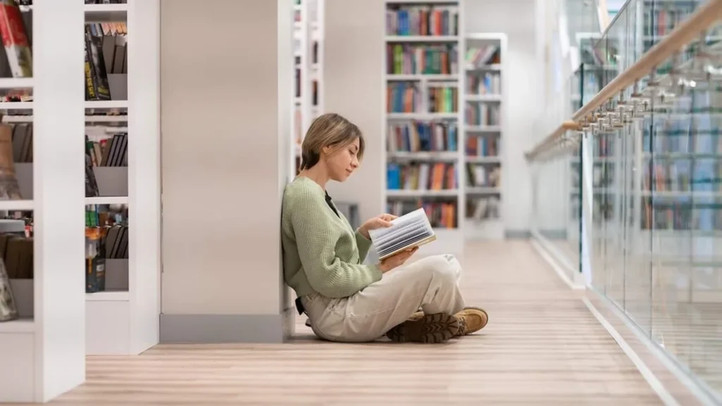 Imagem Mulher lendo um livro na biblioteca do artigo Aprendendo a desvendar o mundo da literatura