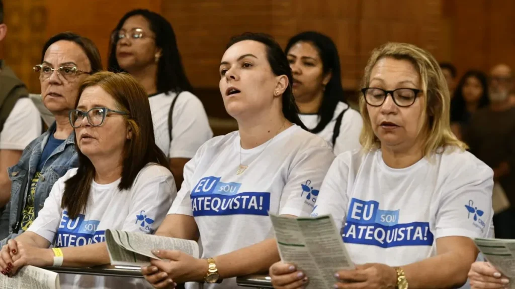 Imagem mulheres na missa segurando o folheto deus conosco do artigo Folheto "Deus Conosco" auxilia a liturgia das Santas Missas há 54 anos