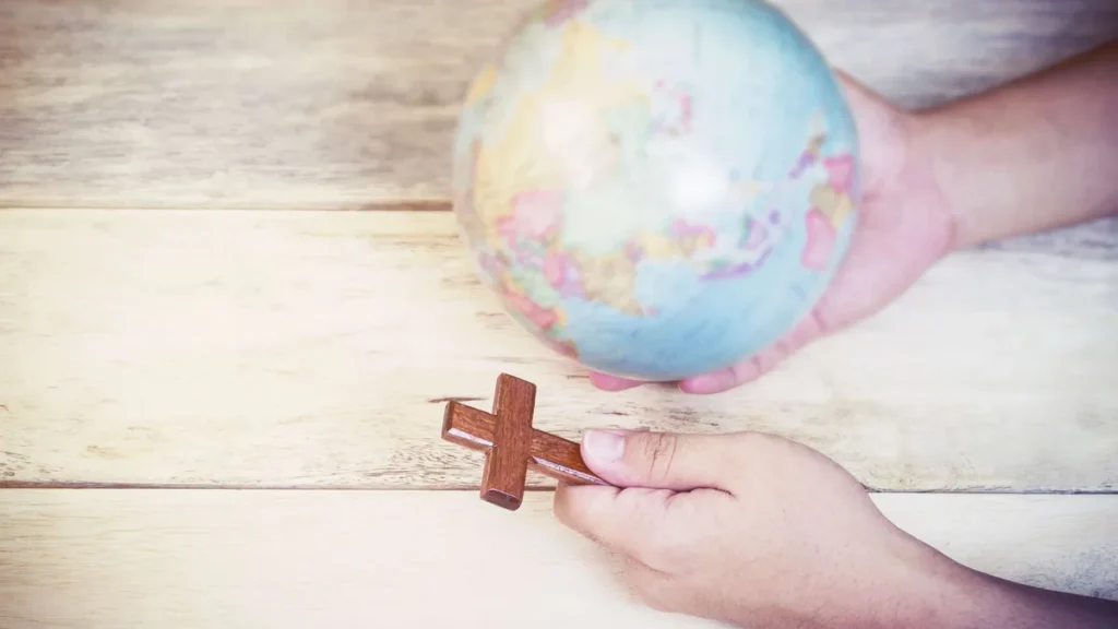 Imagem cruz e o planeta terra sendo segurados por uma pessoa do artigo Oração pelas missões: orando para evangelizar o mundo