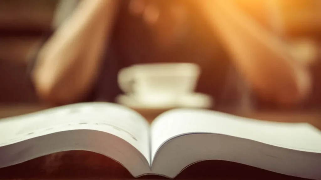 Imagem Biblia aberta com uma caneca ao fundo do artigo 3 versículos para iniciar bem a semana