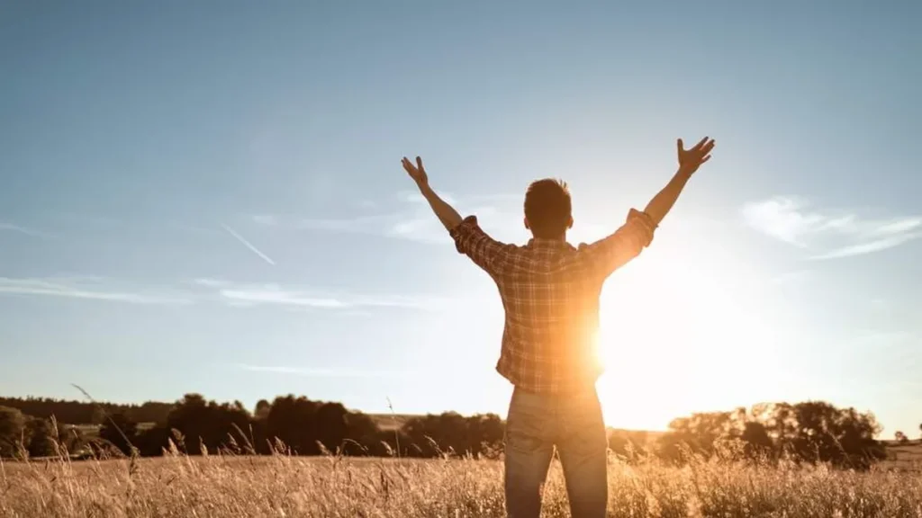 Imagem homem com os bracos para o alto olhando para o ceu do artigo Dogmas da Igreja: A unidade de Deus