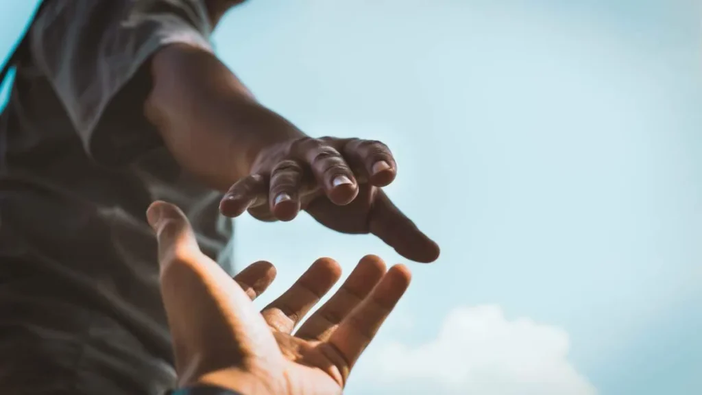 Imagem Uma mao tentando alcancar outra do artigo Ações solidárias da Igreja são a continuidade da missão de Cristo