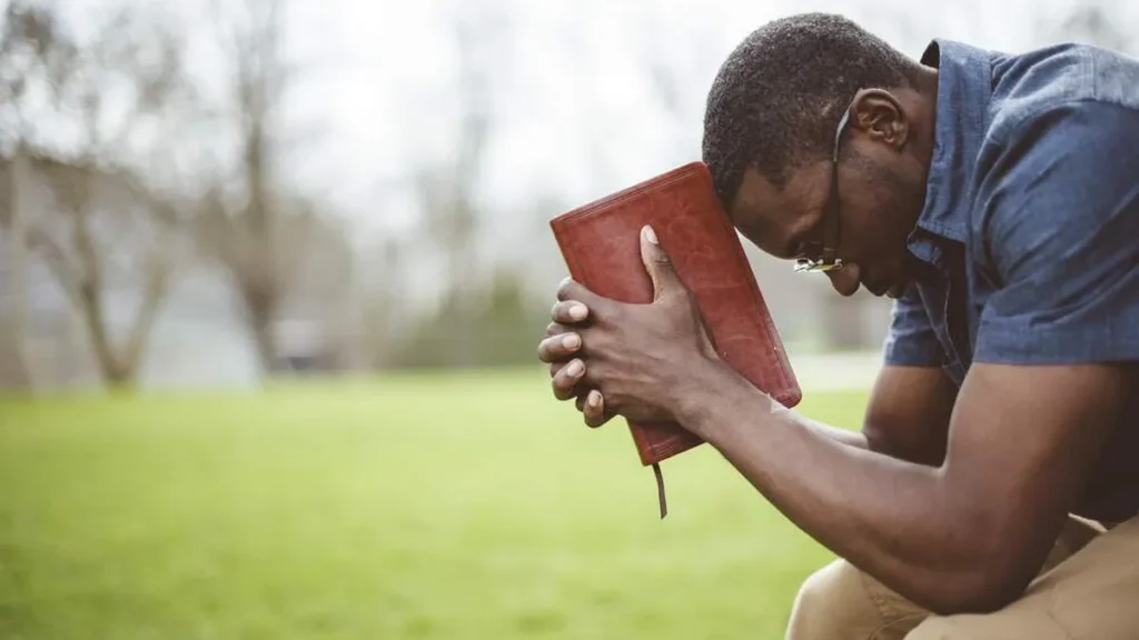 Imagem homem negro segura a biblia em frente ao rosto do artigo 5 versículos para manter-se firme em seu propósito na Quaresma