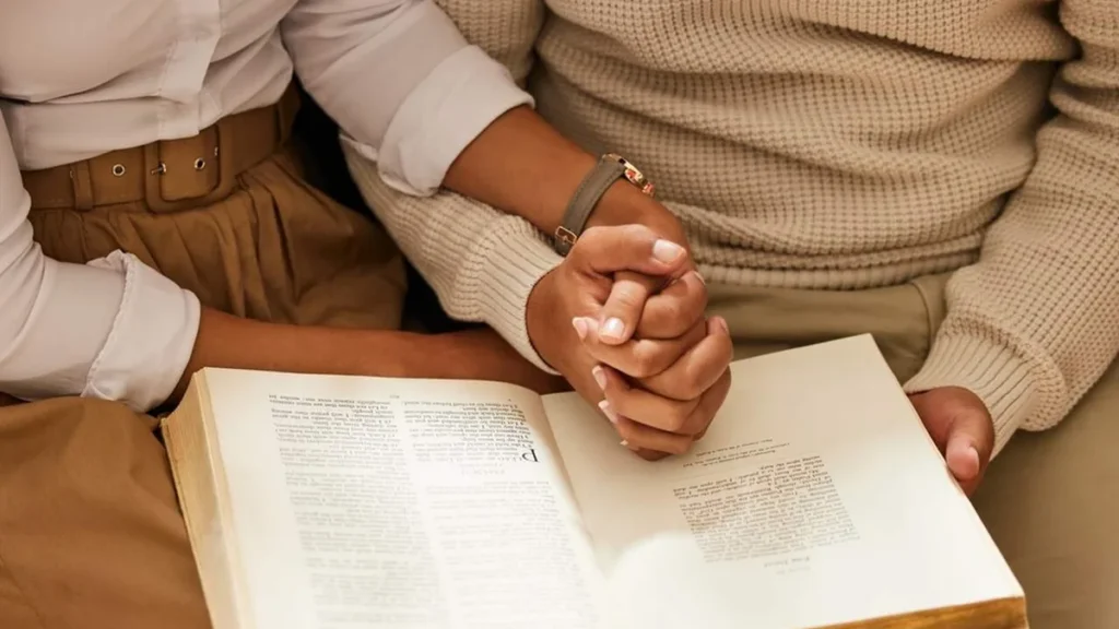 Imagem Maos dadas orando com a Biblia do artigo Conheça as 5 linguagens do amor