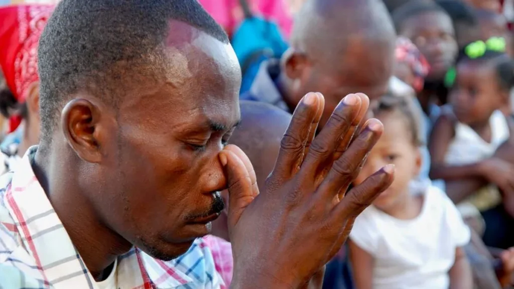 Imagem Homem reza com as maos postas na capital do Haiti Porto Principe do artigo Dia de Oração pelo Haiti: solidariedade e esperança