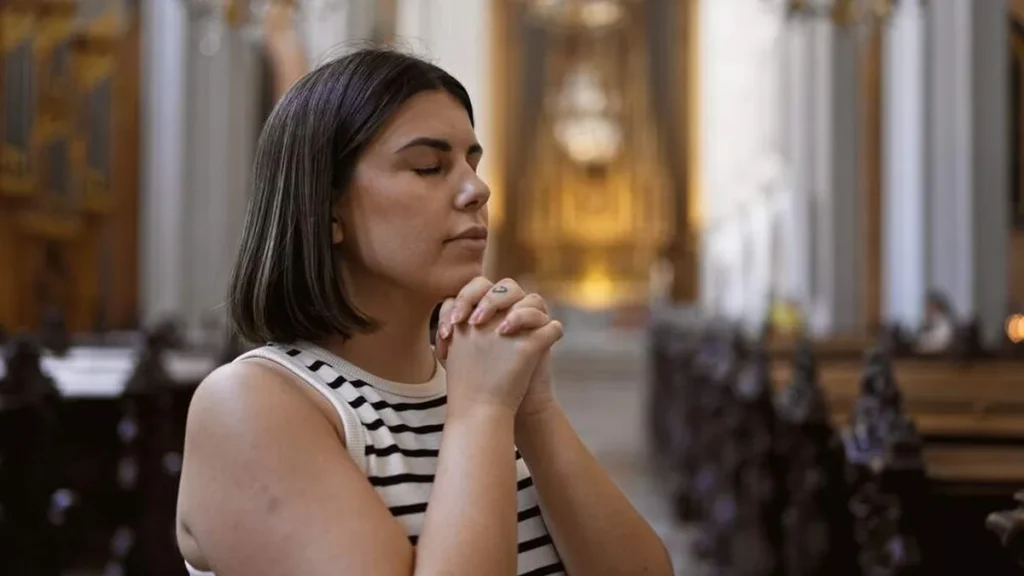 Imagem mulher rezando dentro da igreja do artigo Deus tem espaço no seu dia?