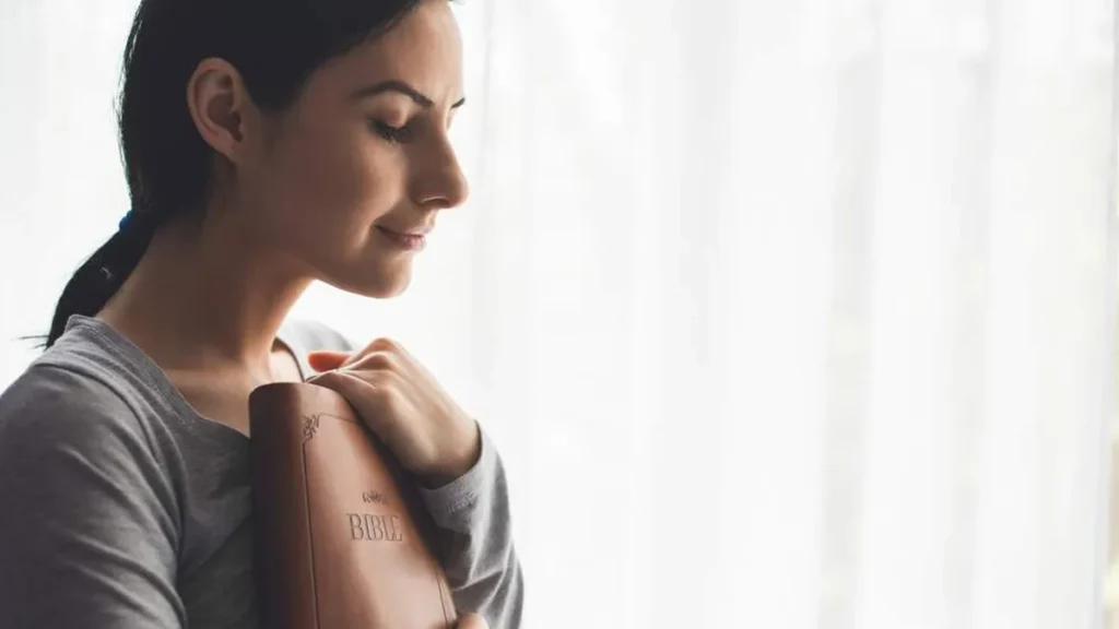 Imagem moca abracando a biblia contra o peito do artigo 7 versículos da Bíblia para encontrar o seu amor próprio