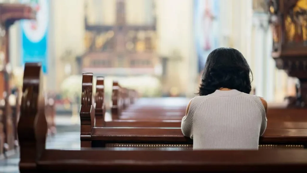 Imagem pessoa rezando na igreja do artigo Deus realmente escuta as orações dos pecadores?