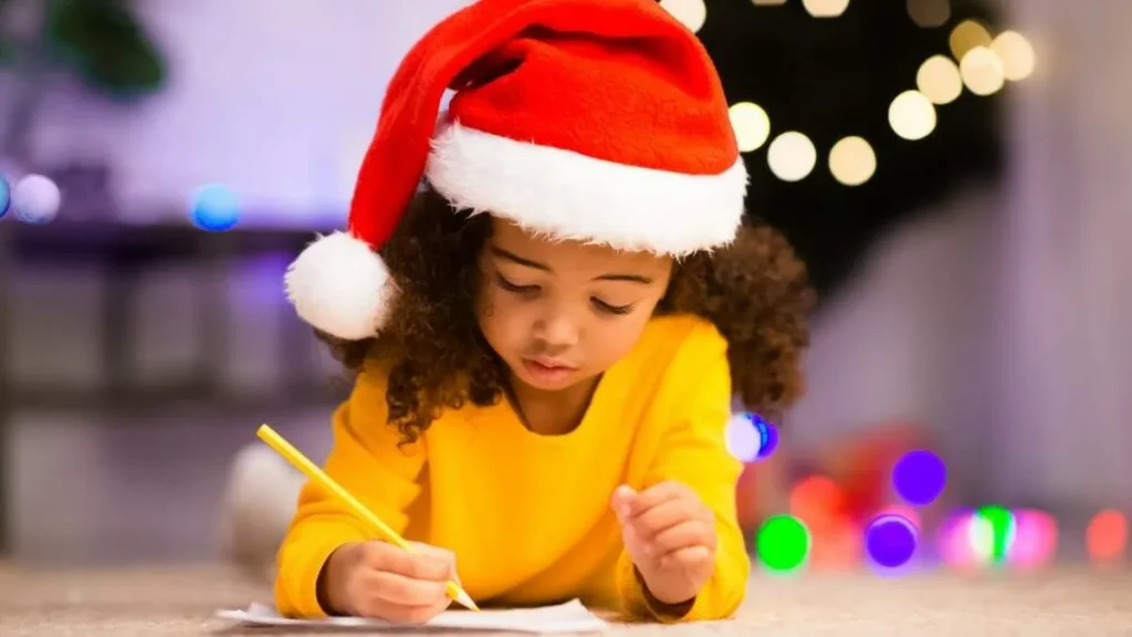 Imagem menina escrevendo carta de natal com touca natalina na cabeca do artigo Que tal escrever uma cartinha para o Menino Jesus?