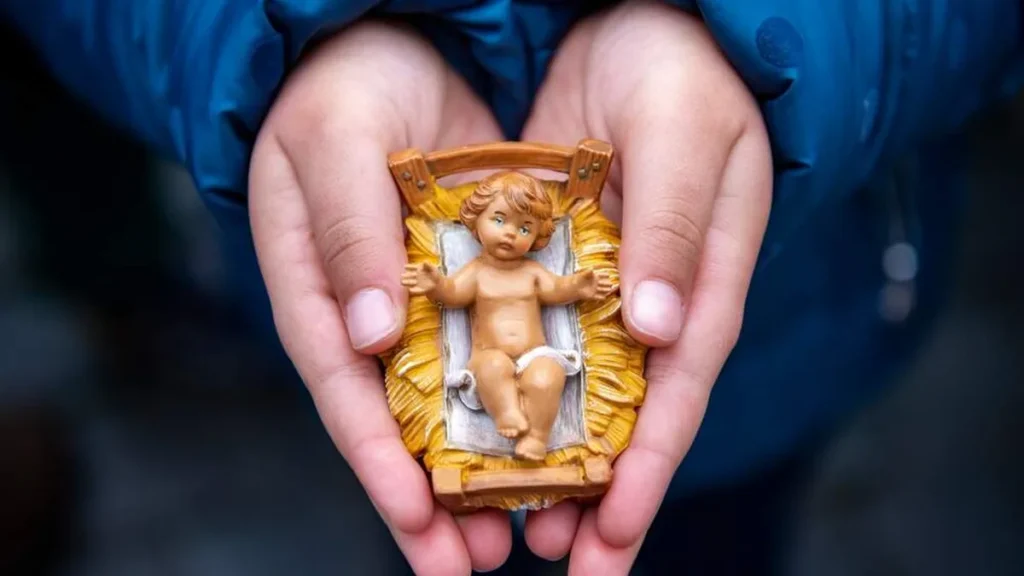 Imagem menino jesus na manjedoura segurado por uma mao do artigo Faça prece de Santo Afonso para o Menino Jesus