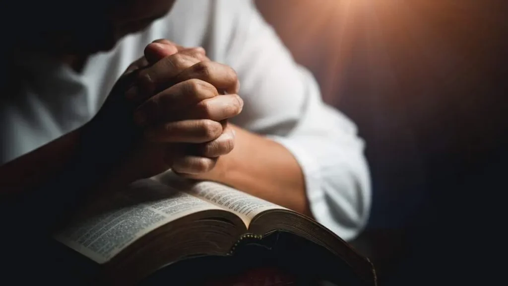 Imagem Maos rezando sob a Biblia do artigo Comece o ano entregando seus planos para Deus