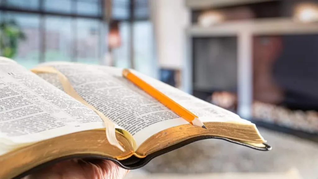 Imagem Maoes segurando uma Biblia aberta com um lapis em cima do artigo Participe do 2º Congresso Nacional da Animação Bíblica da Pastoral