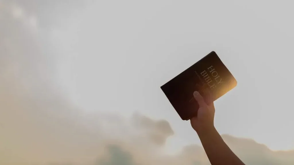 Imagem pessoa com o braco erguido segurando a biblia do artigo Juristas católicos se unem em prol da justiça pela fé