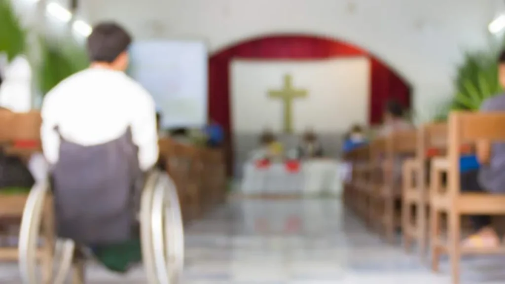 Imagem pessoa com deficiencia em uma cadeira de rodas olhando para o altar em uma igreja do artigo Acolher e evangelizar: como você tem vivido essa missão?