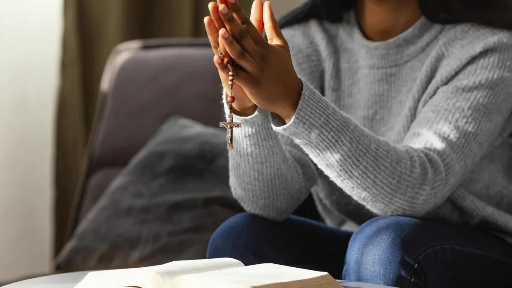 Imagem mulher rezando o terco com biblia sobre a mesa do artigo A verdadeira alegria vem de Deus