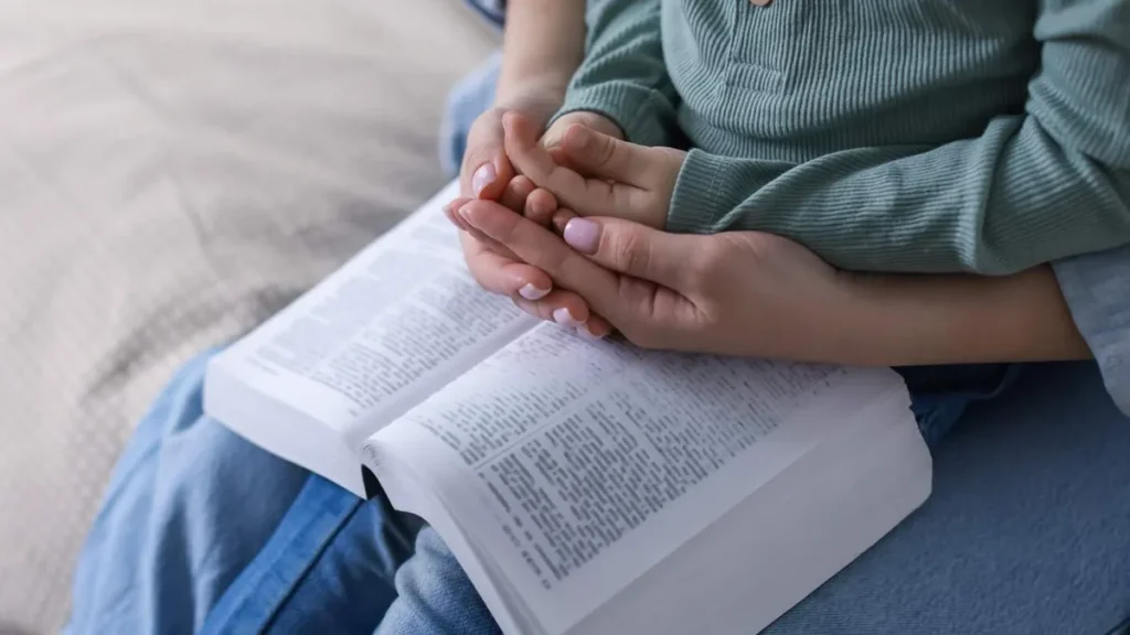 Imagem mae e filho com a biblia no colo rezando juntos do artigo Tenha um devocionário para as mães intercederem pelos filhos