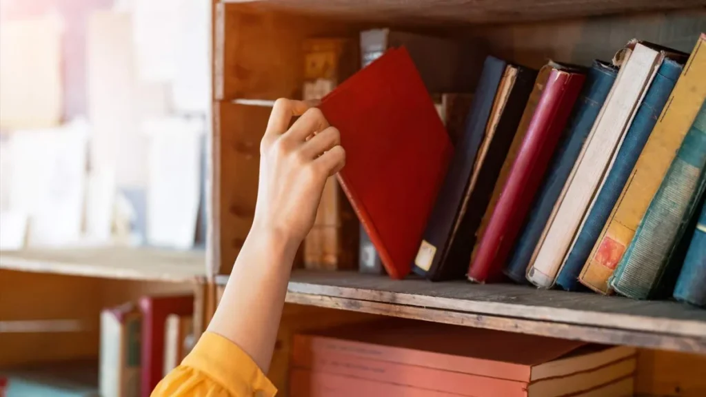Imagem moca pegando livro da estante do artigo Aprenda algo novo nas férias: 5 assuntos para se aprofundar!
