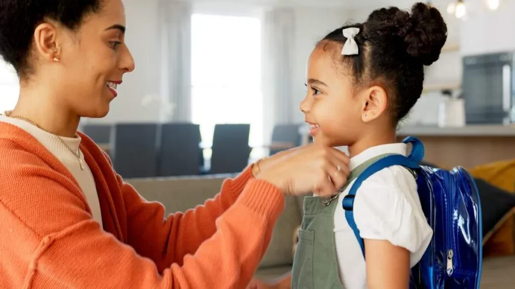 Mãe prepara filha para a escola. Volta das férias pode ser momento estressante para a família!