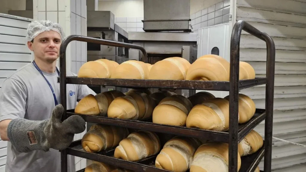 Imagem Padeiro da Casa do Pao do Santuario Nacional com uma forma de paes de Nossa Senhora do artigo Casa do Pão: Das mãos dos colaboradores ao coração dos devotos