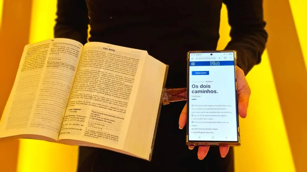 Imagem biblia fisica e online sendo seguradas em maos de uma mulher do artigo A12 recorda 10 anos da Bíblia de Aparecida on-line