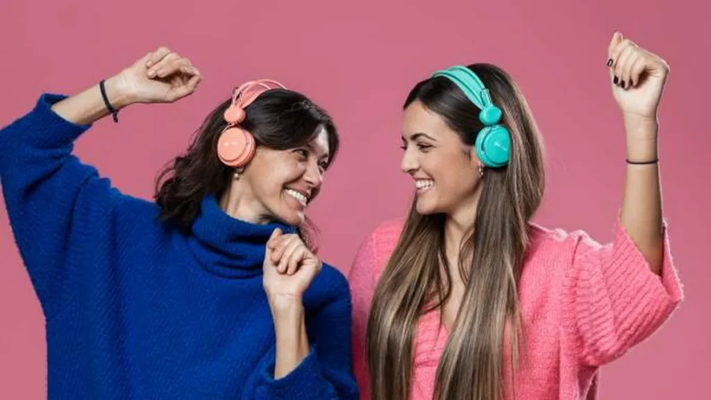 Imagem duas mocas dancam felizes se olhando com o fone de ouvido na cabeca imagem utilizada para o almanaque da radio aparecida do artigo Duetos que marcaram gerações e emocionam até hoje