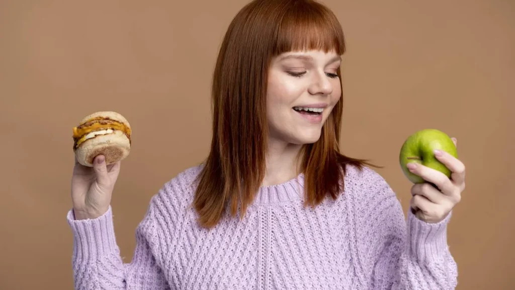 Imagem Mulher escolhendo entre um doce e uma maca o que vai comer do artigo Nutrição emocional: alimentação no bem-estar psicológico