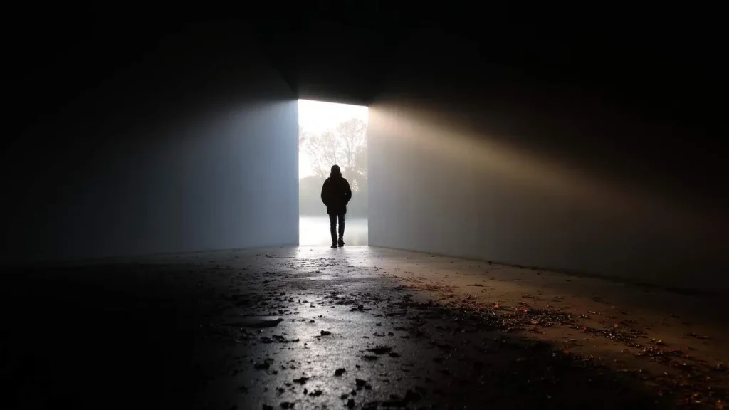 Imagem homem na porta na luz do artigo Como a fé pode ser canal para a superação do luto?